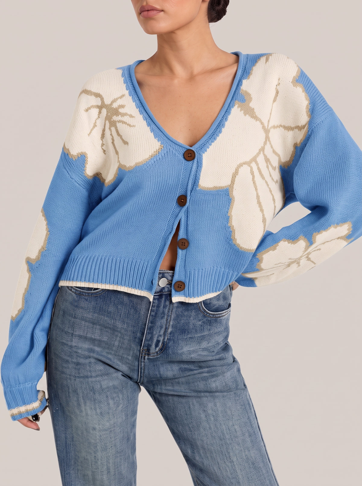 Blue V-neck button-front cropped knit cardigan with large cream flower motifs outlined in tan, front view