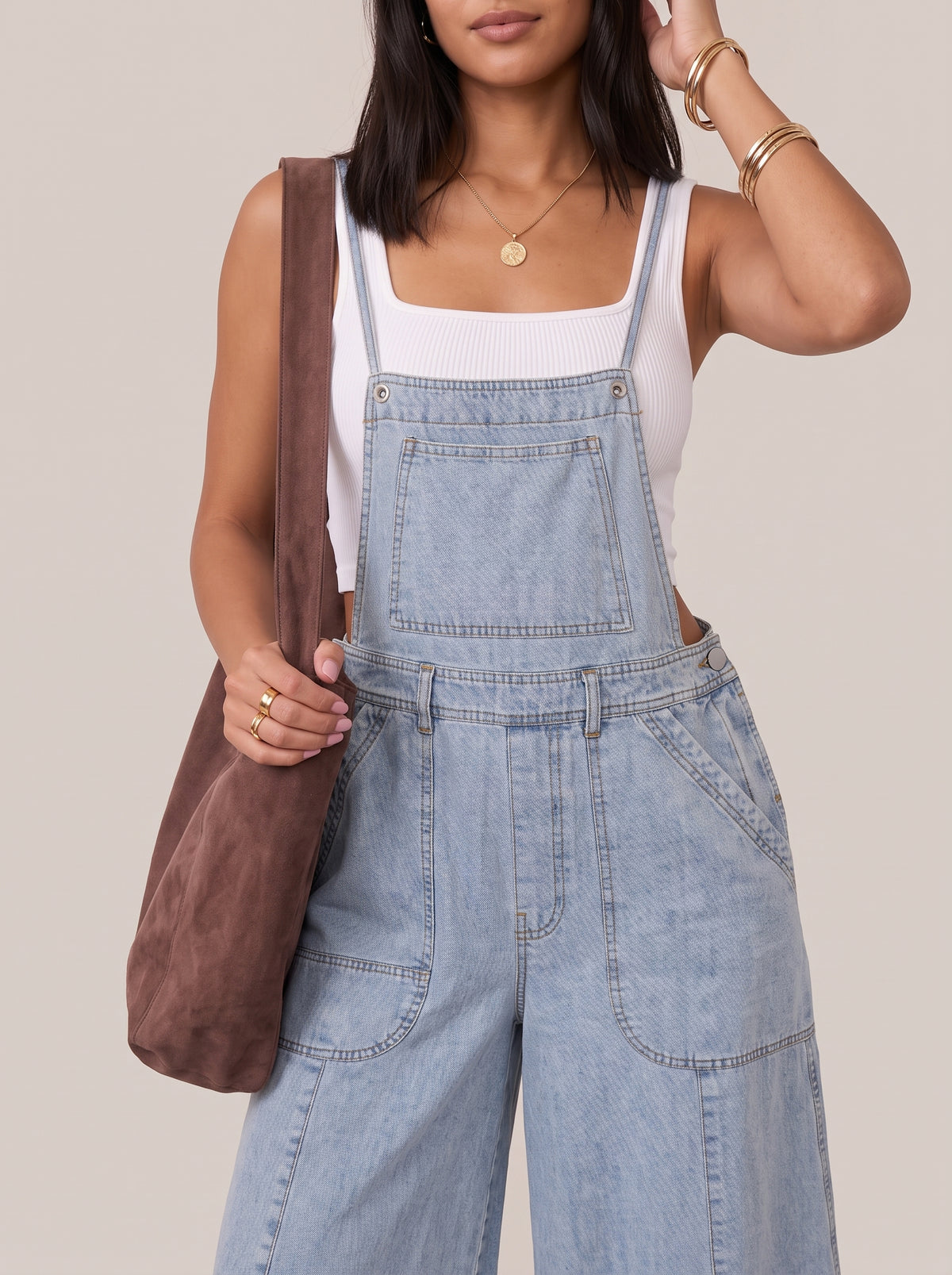 Close view of the light blue denim overalls bib, chest pocket and waist seam