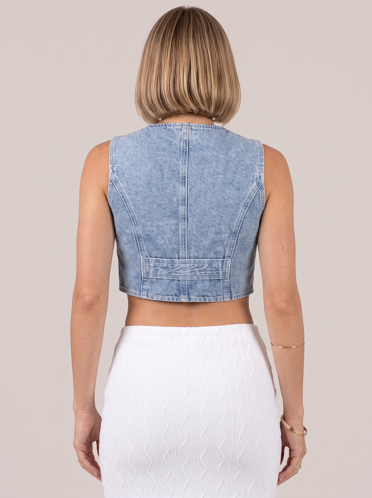 Back of the light blue sleeveless denim top showing the half belt strap at the waist