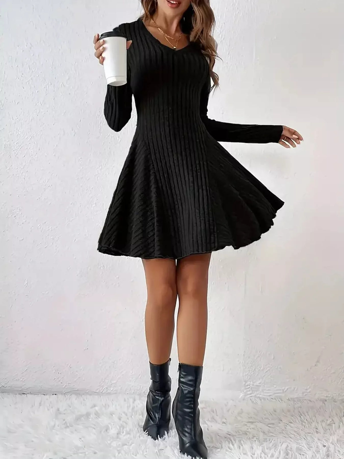 Black ribbed knit flared mini dress with the skirt swinging, front view
