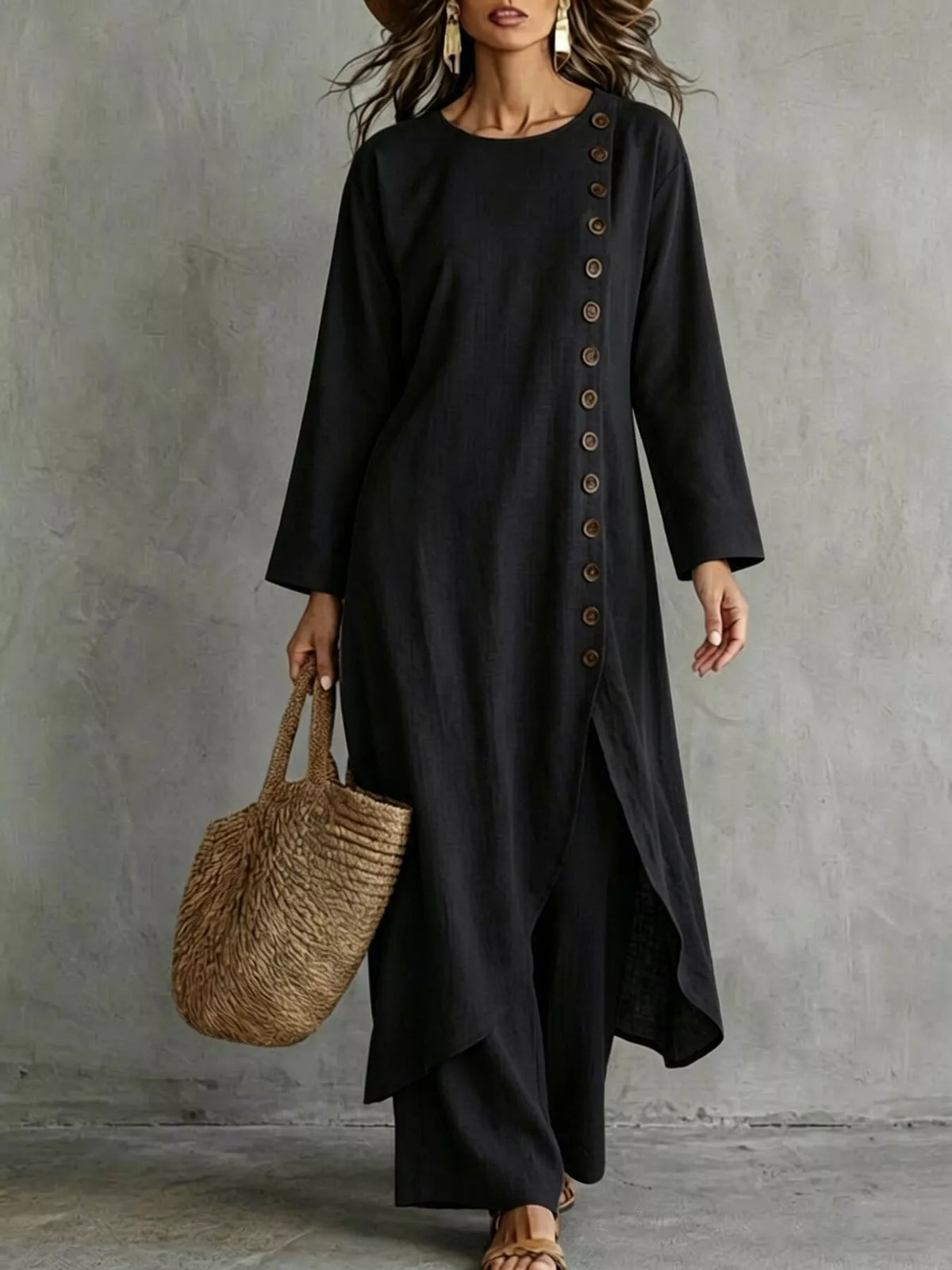 Black longline top with a row of buttons down one side and a slit hem, worn with matching pants, front view