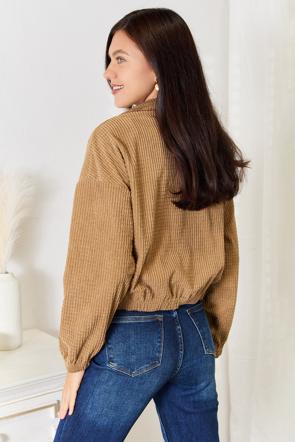 Back view of the camel cropped jacket with dropped shoulders, long sleeves and a gathered hem and cuffs
