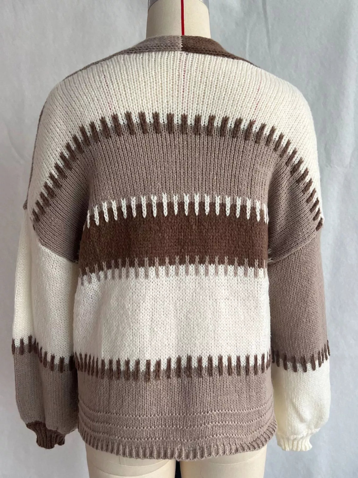 Back view of the brown, taupe and cream striped knit cardigan on a dress form, with jagged stitched stripe edges and ribbed cuffs
