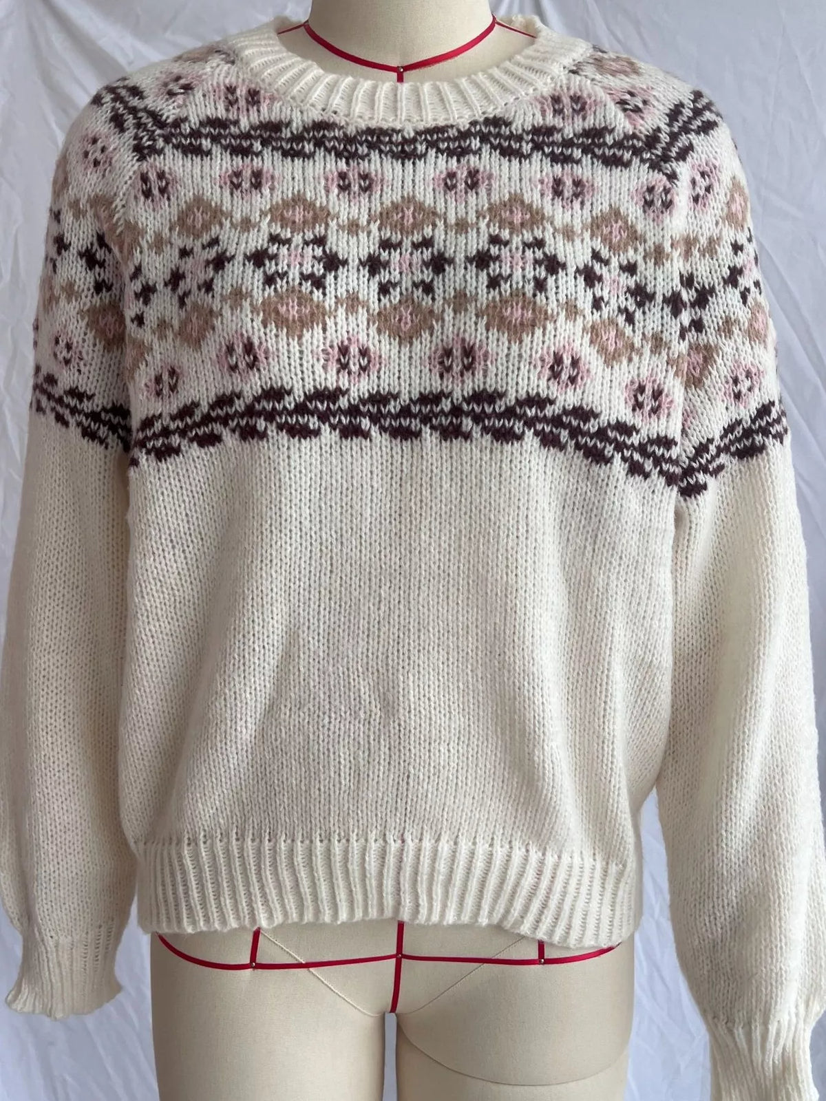 Cream fair isle round neck sweater on a dress form, front view, with a dark brown, taupe and soft pink patterned yoke and ribbed neckline, cuffs and hem