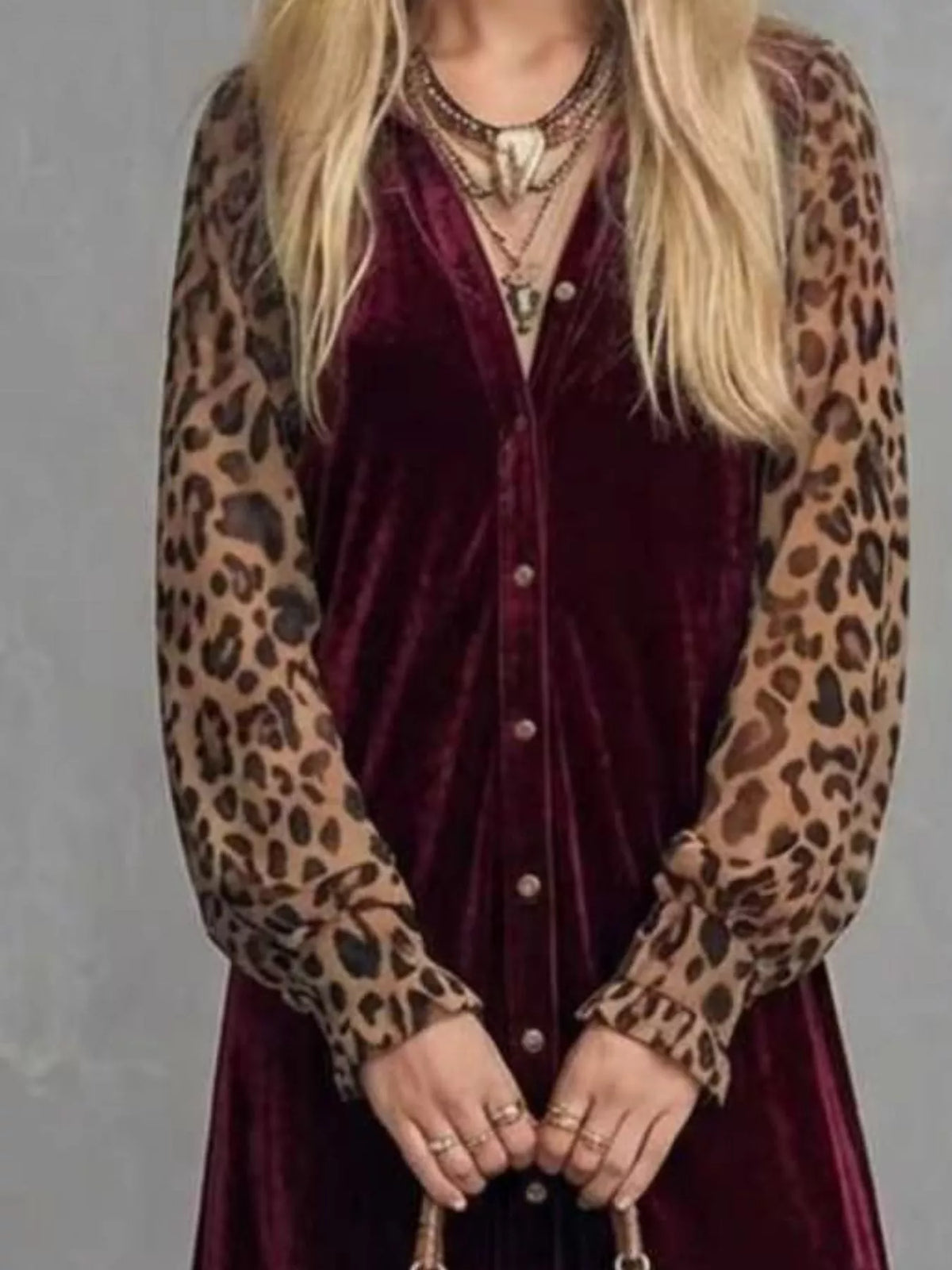 Close-up of the buttoned bodice and leopard print sleeve cuffs of a burgundy velvet maxi dress