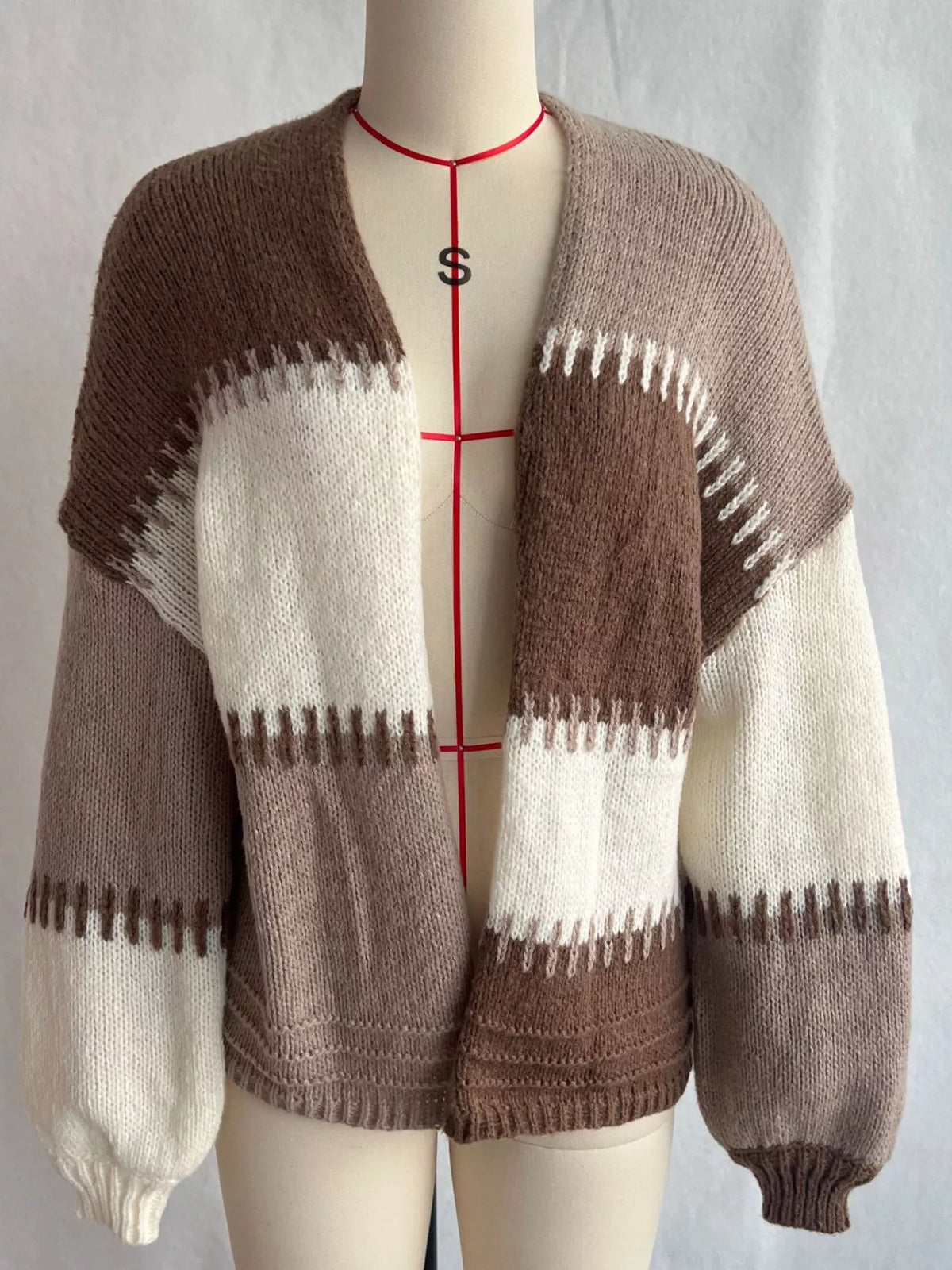 Brown, taupe and cream colour-block knit cardigan shown open on a dress form, front view with dropped shoulders and balloon sleeves