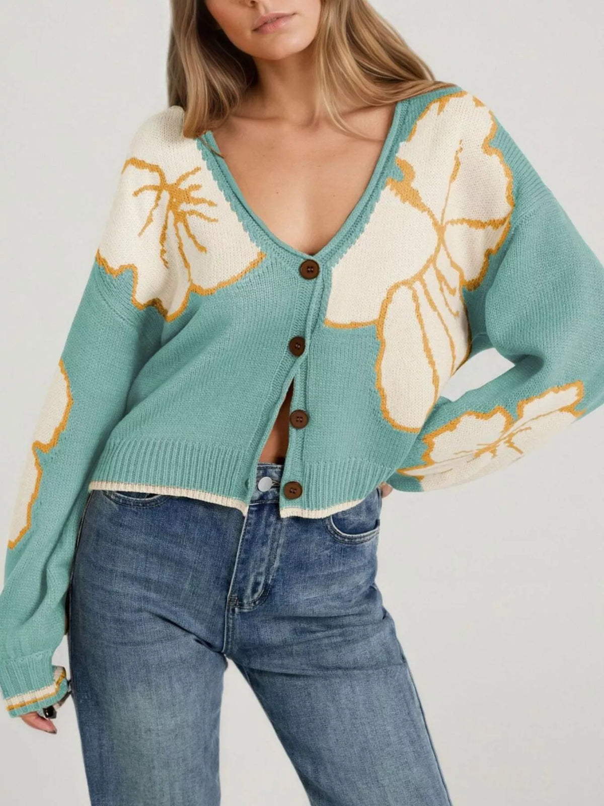 Green V-neck button-front cropped knit cardigan with large cream flower motifs outlined in mustard, front view
