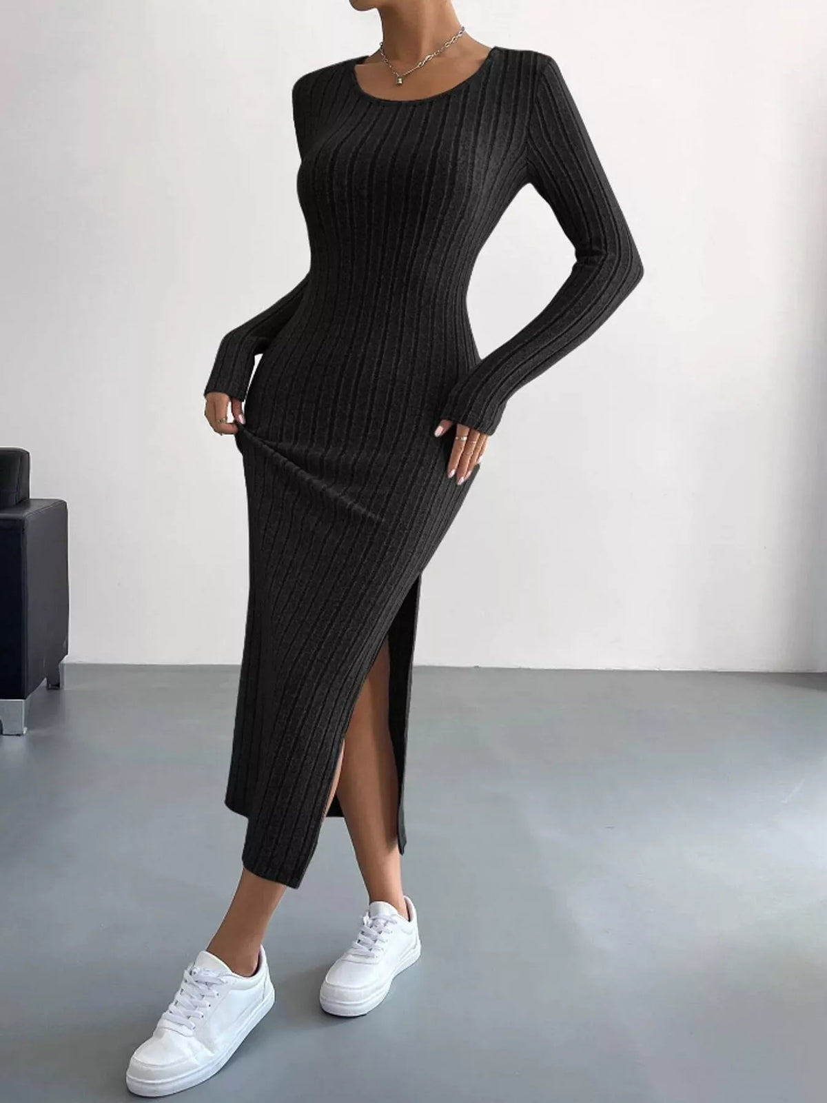 Black ribbed knit long-sleeve midi dress with one hand lifting the skirt to show the side slit