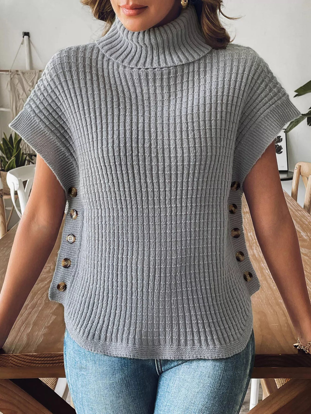 Grey short sleeve ribbed turtleneck sweater with a row of buttons down each side and a curved hem, front view