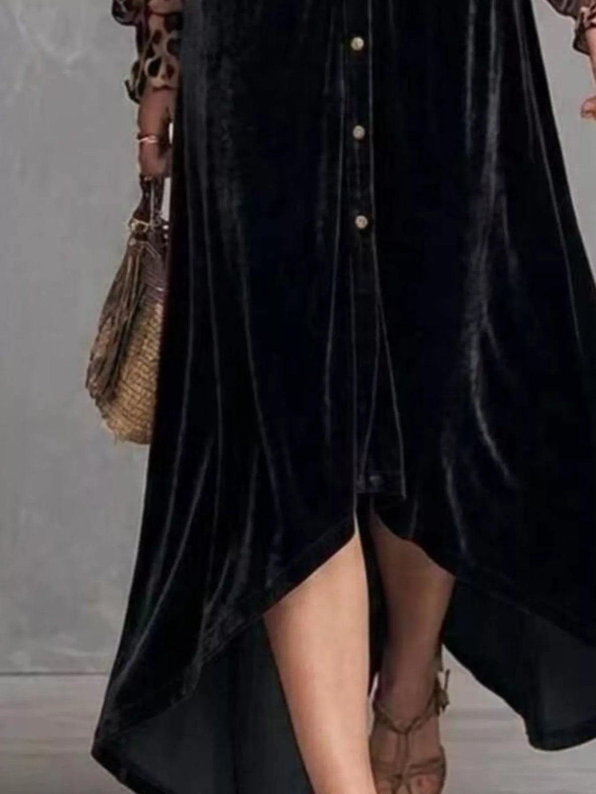 Close-up of the high-low hem and buttons of a black velvet maxi dress