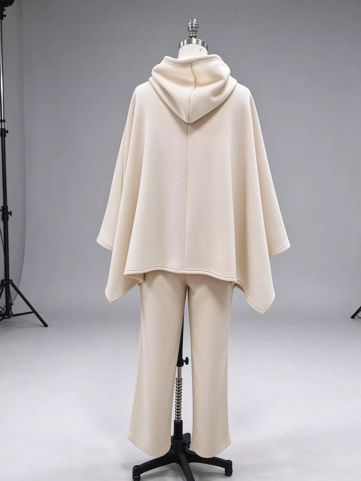 Back view of the beige hooded poncho top with a centre back seam and matching wide-leg pants on a dress form