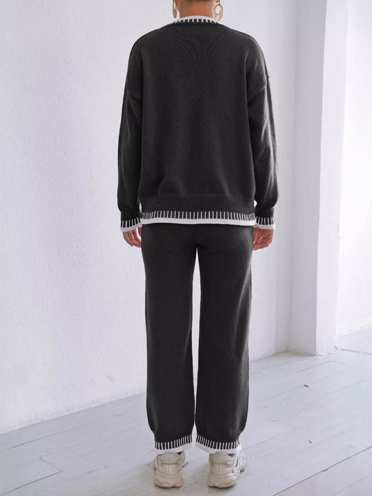 Back view of the Black knit sweater and pants set with white contrast stitching at the hem and cuffs