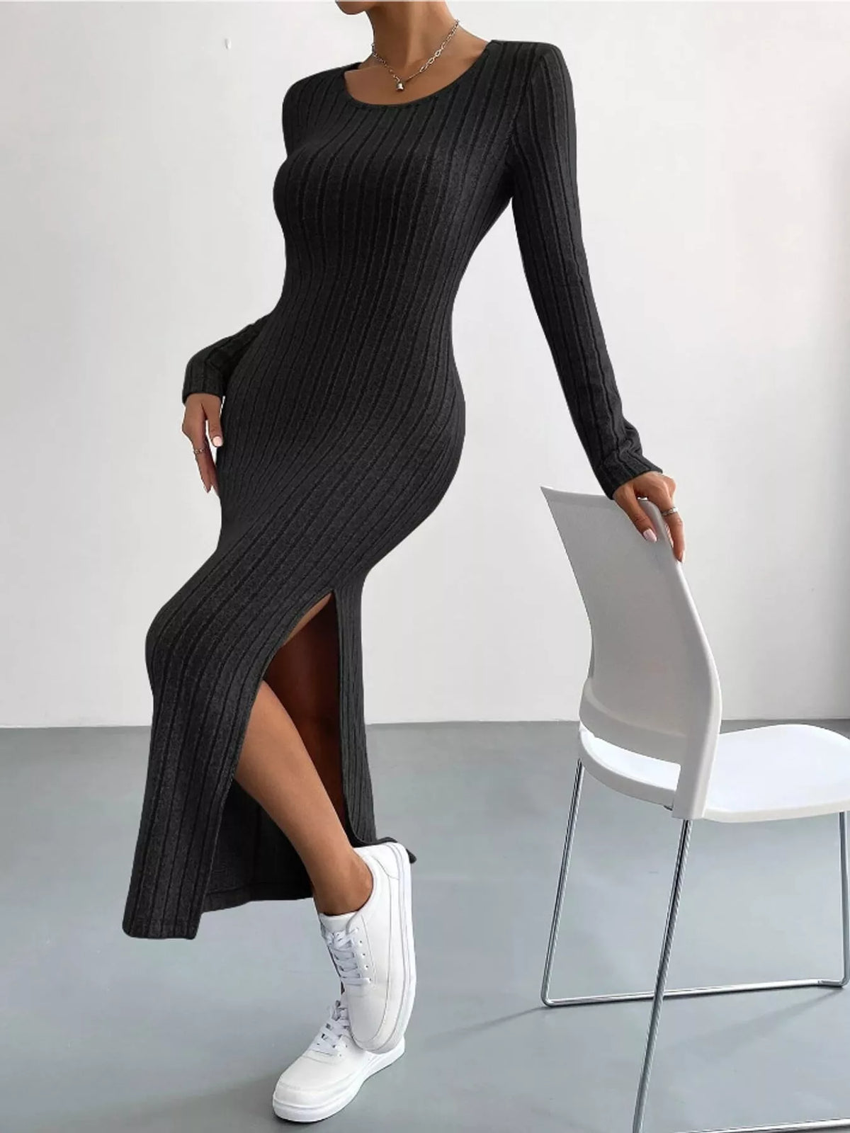 Black ribbed knit long-sleeve midi dress, side slit shown with one leg raised