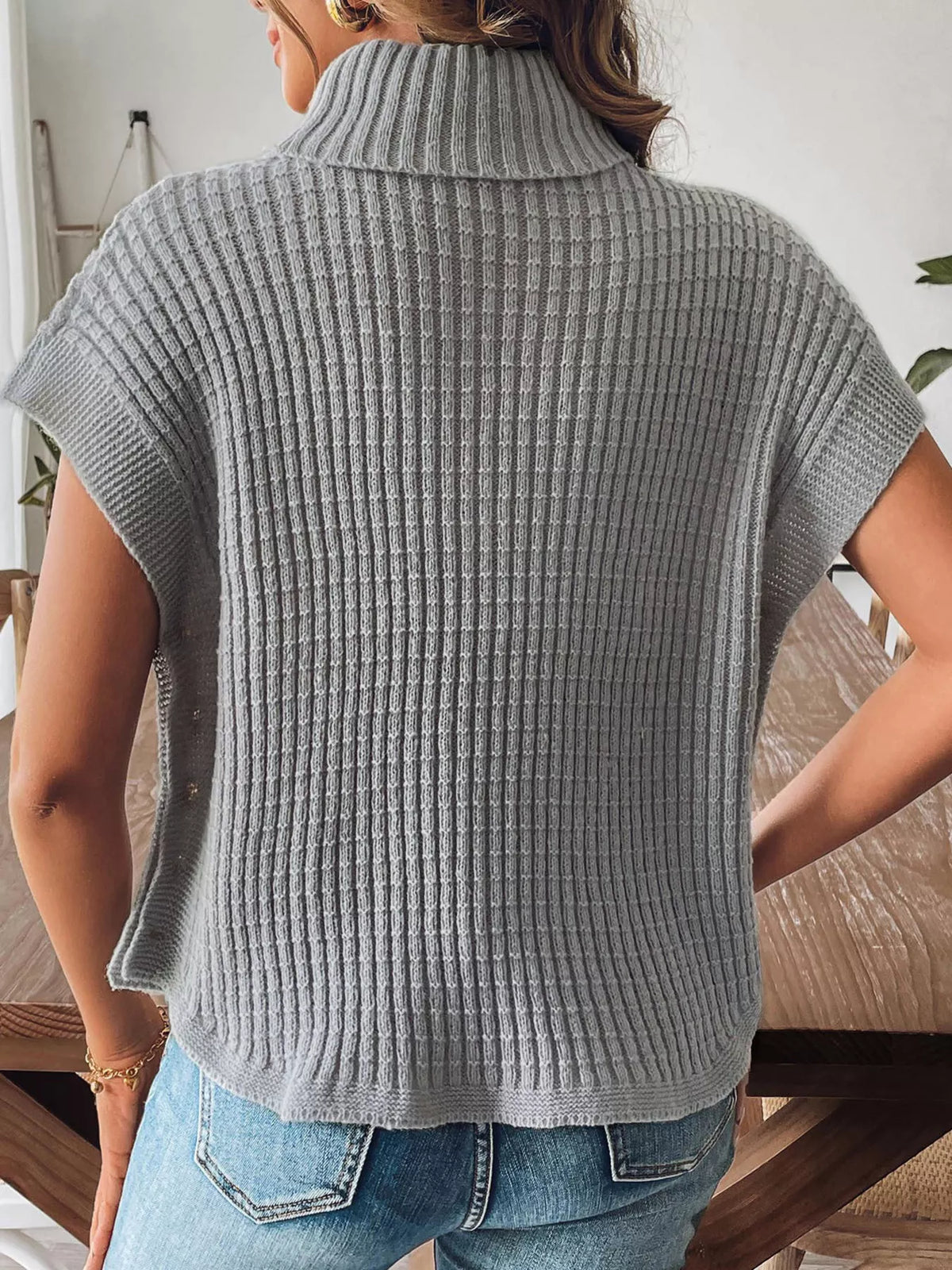 Back view of the grey short sleeve ribbed turtleneck sweater with a curved hem