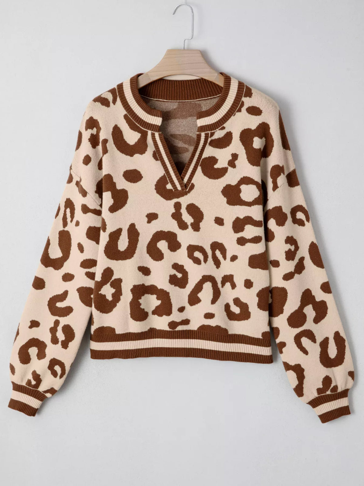 Leopard print notched neck sweater on a hanger, front view showing the full shape and striped trim