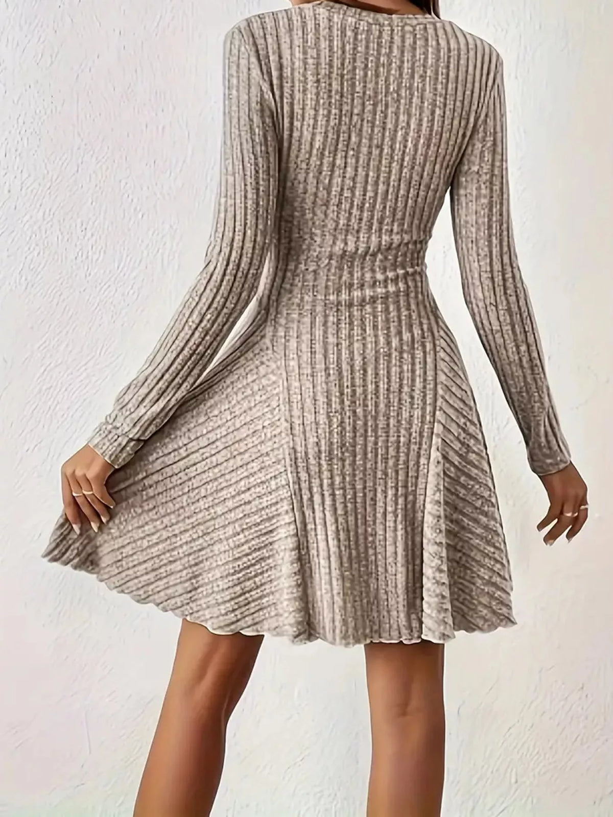 Back view of the Apricot ribbed knit long-sleeve flared dress with one hand on the skirt