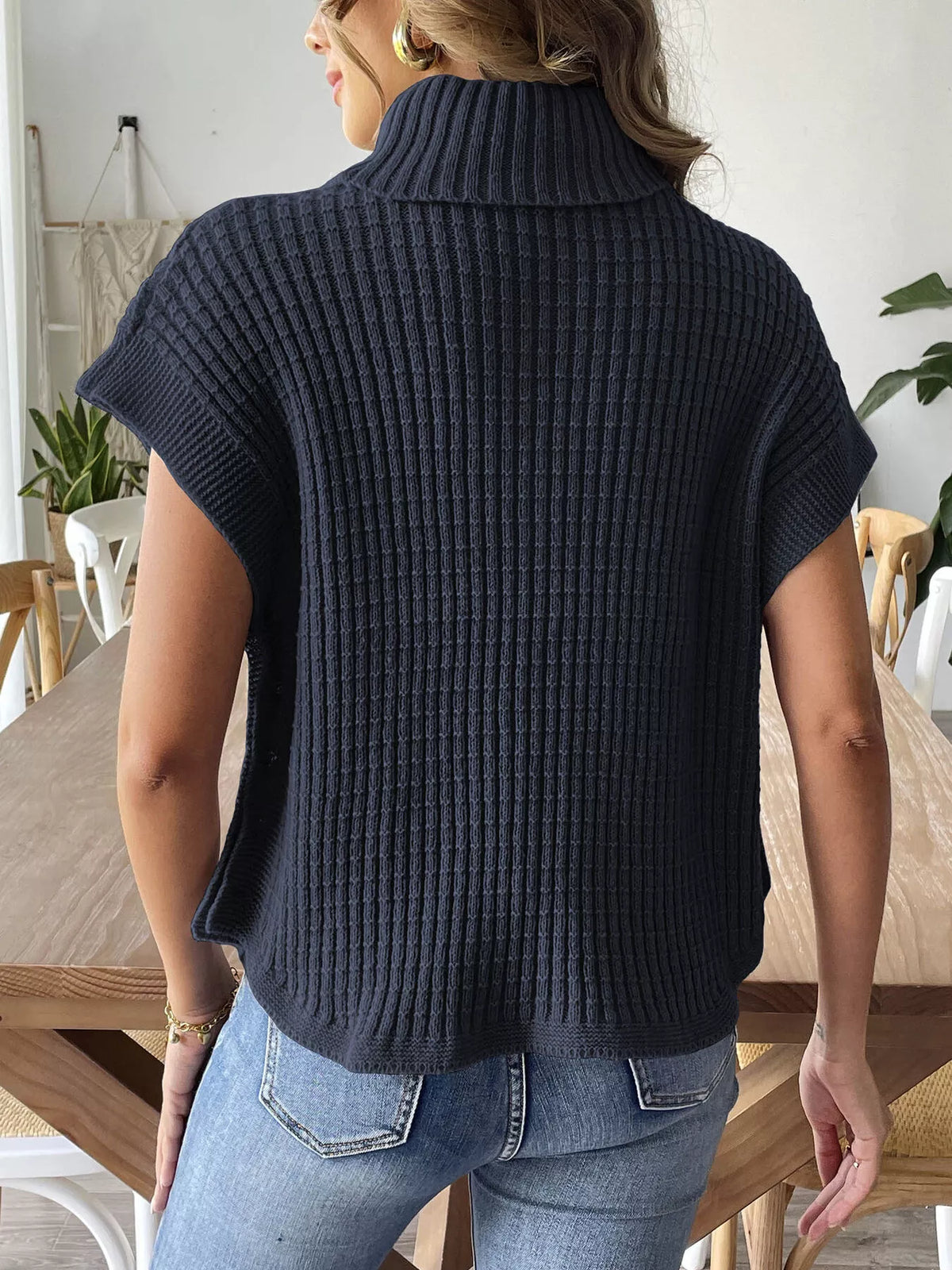 Back view of the navy blue ribbed turtleneck sweater with short sleeves and a curved hem