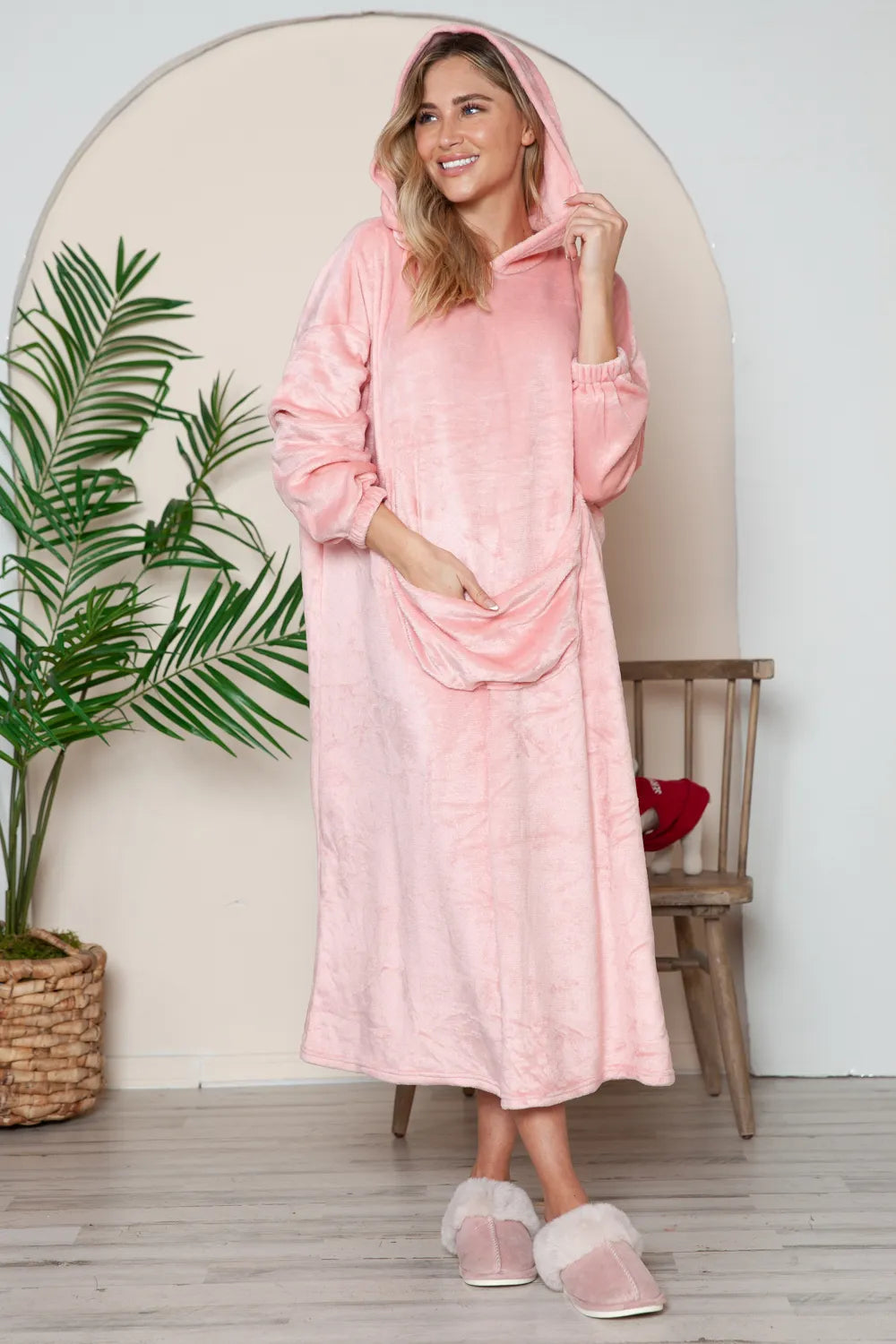Woman in a dusty pink plush-texture hooded midi lounge dress with large front pocket