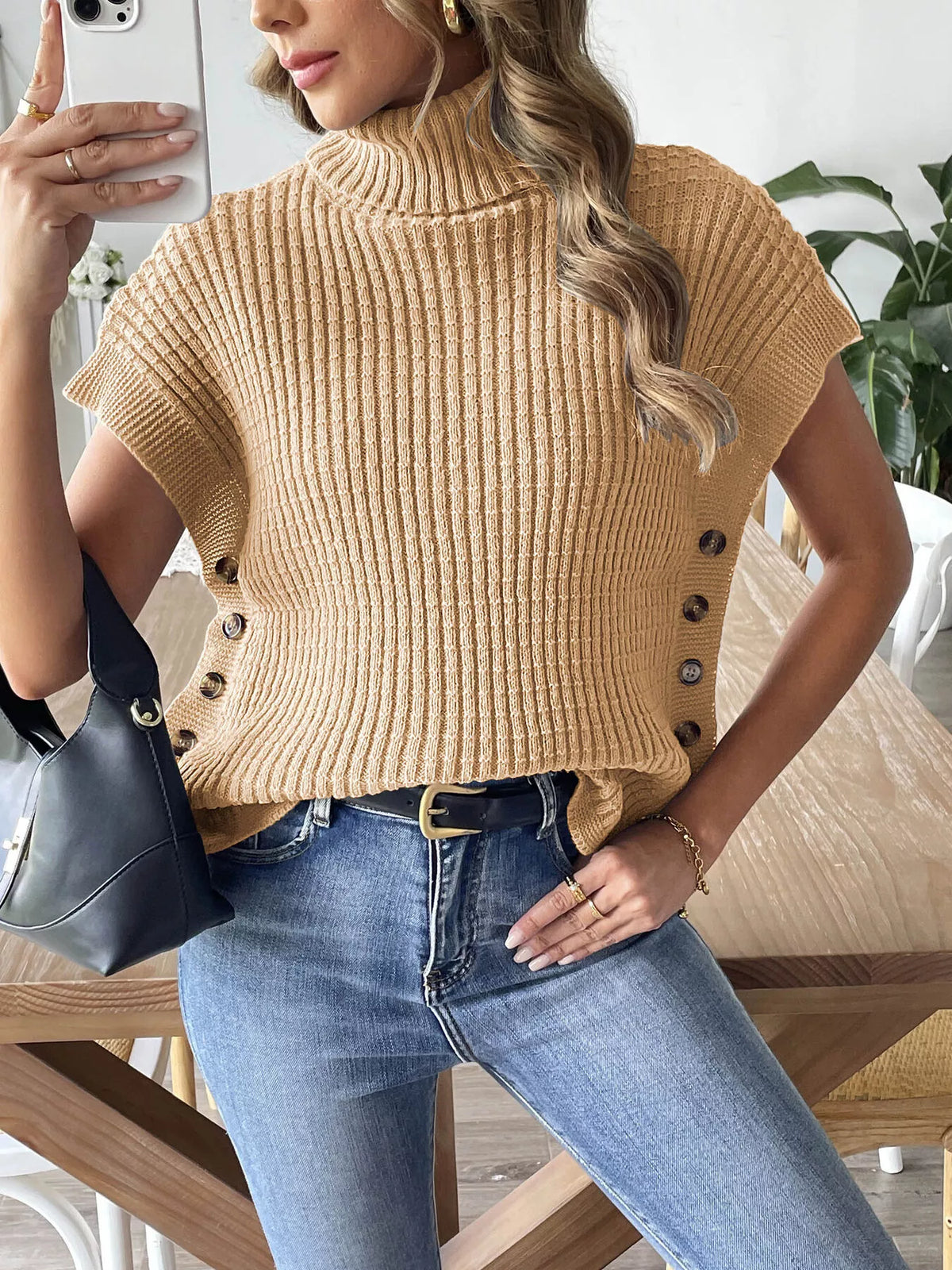 Camel ribbed turtleneck sweater with short sleeves and a row of buttons down each side, worn with jeans