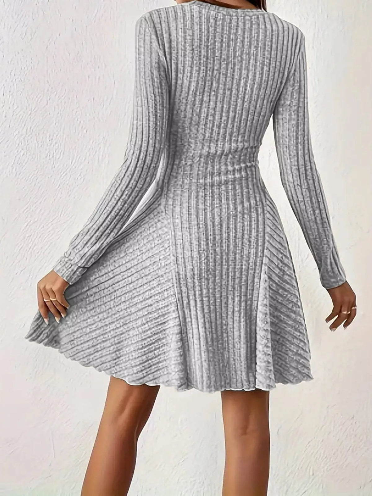 Back view of the Light Gray ribbed knit long-sleeve flared dress with one hand on the skirt
