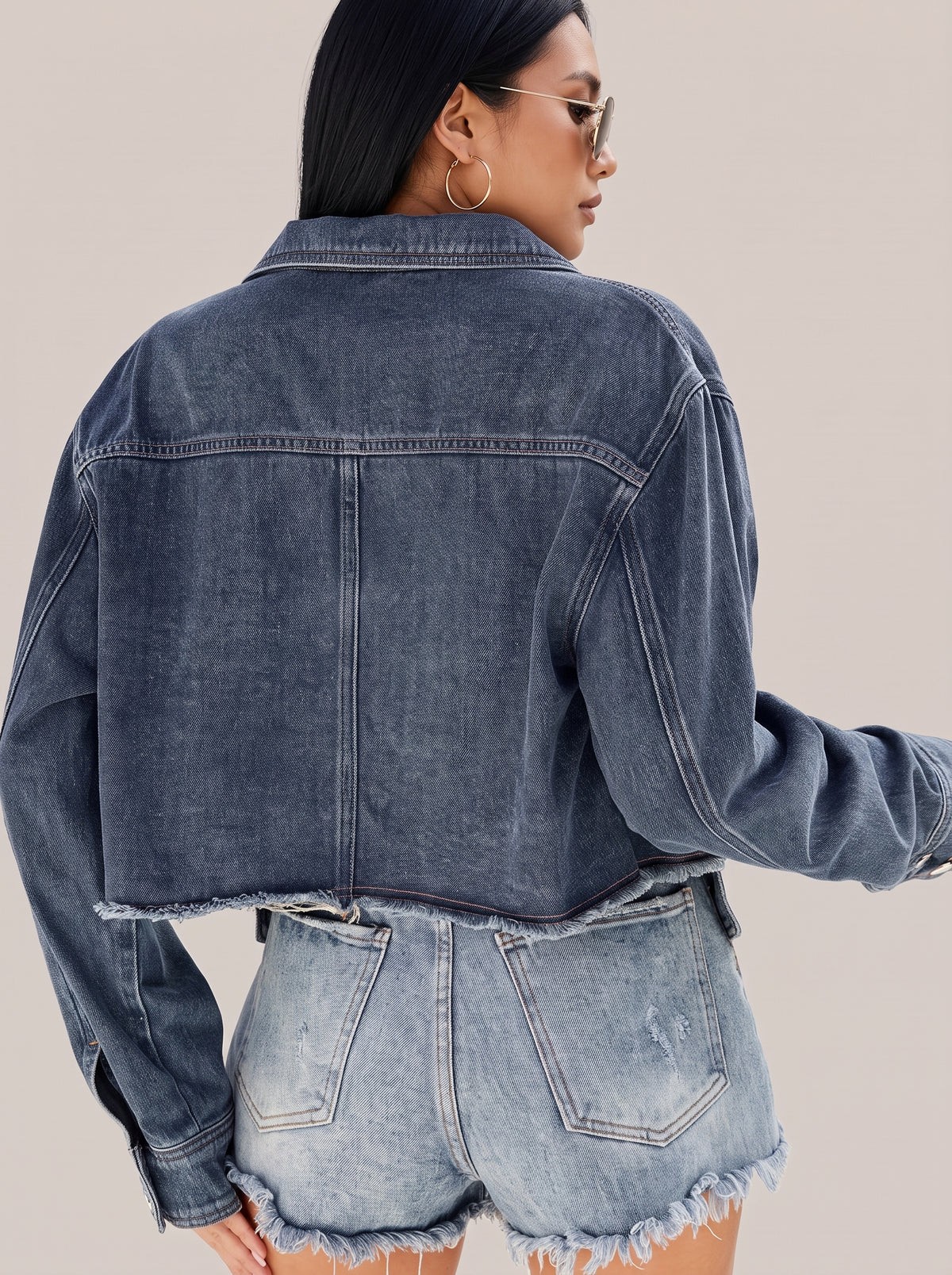 Back of the navy button up denim jacket showing the faded wash and frayed hem