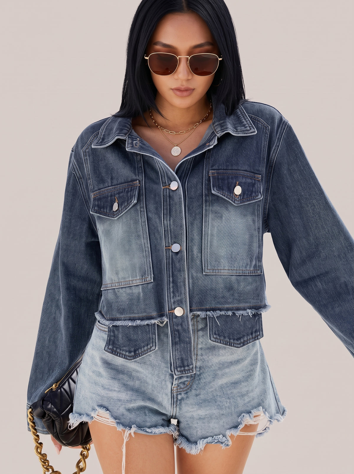 Close view of the navy denim jacket chest pocket, buttons and frayed lower pocket line