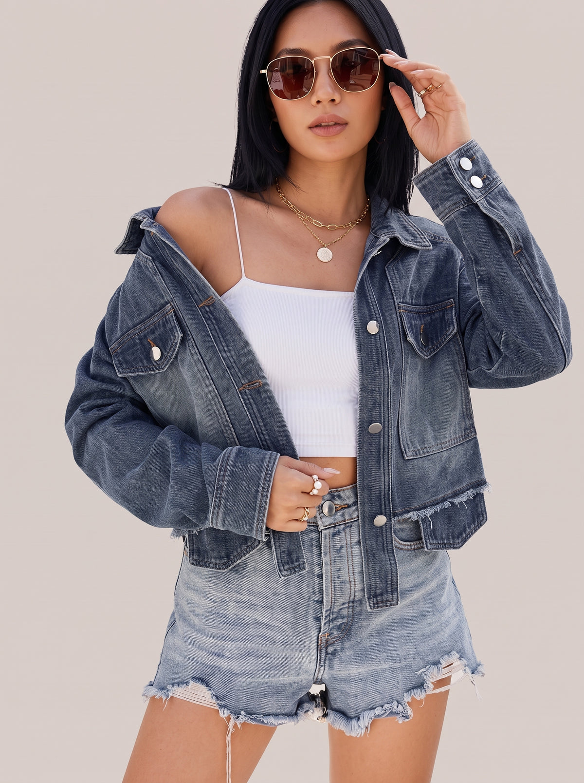 Navy button up denim jacket worn off one shoulder, side view