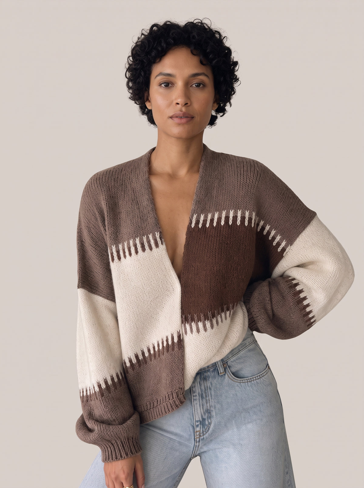 Brown, taupe and cream colour-block knit cardigan with a deep V-neck and jagged white and brown stitched stripe edges, worn open at the front (Brown option)