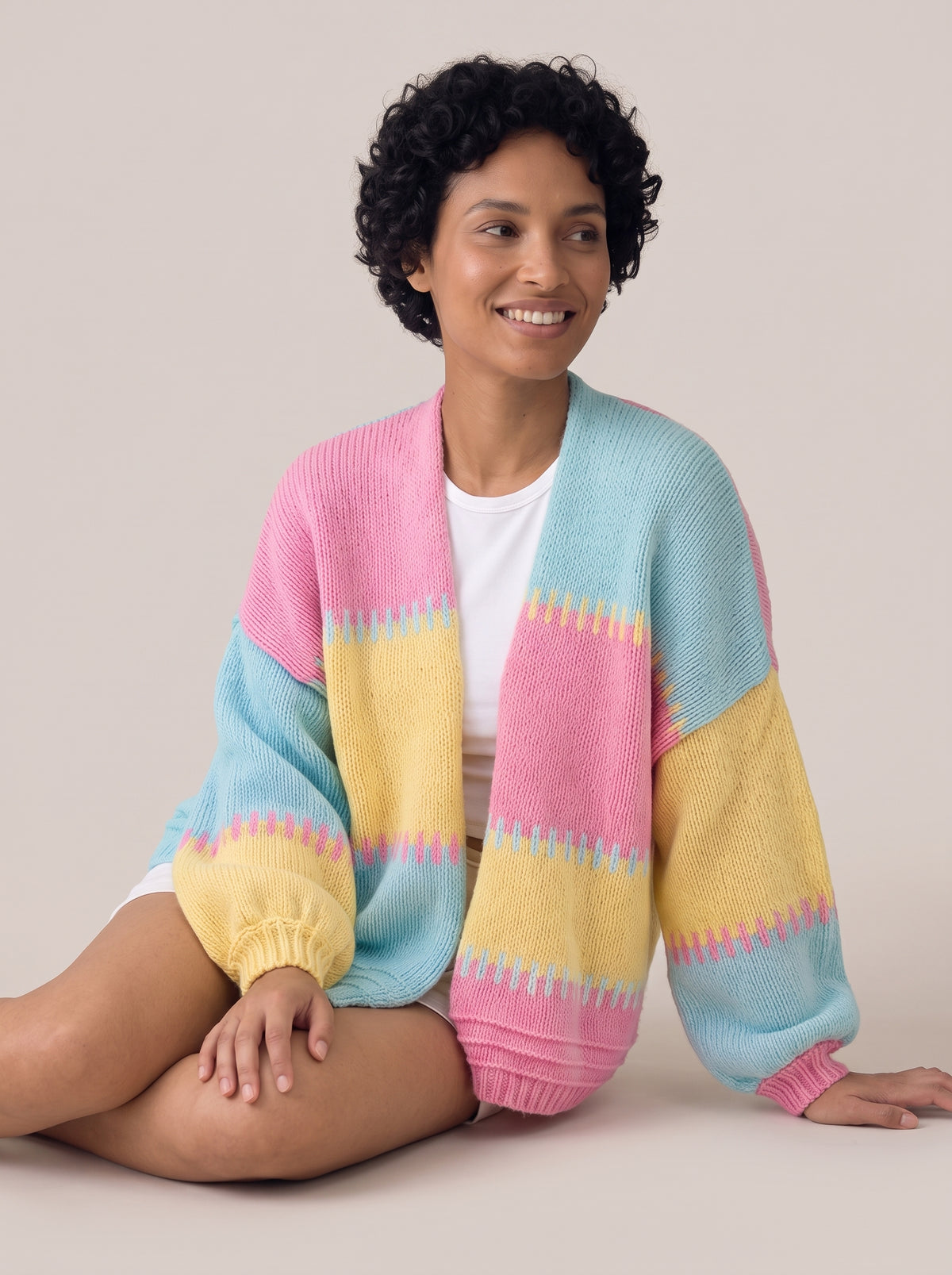 Pastel pink, yellow and aqua colour-block knit cardigan with jagged stitched stripe edges and balloon sleeves, worn open over a white top (Pink option)