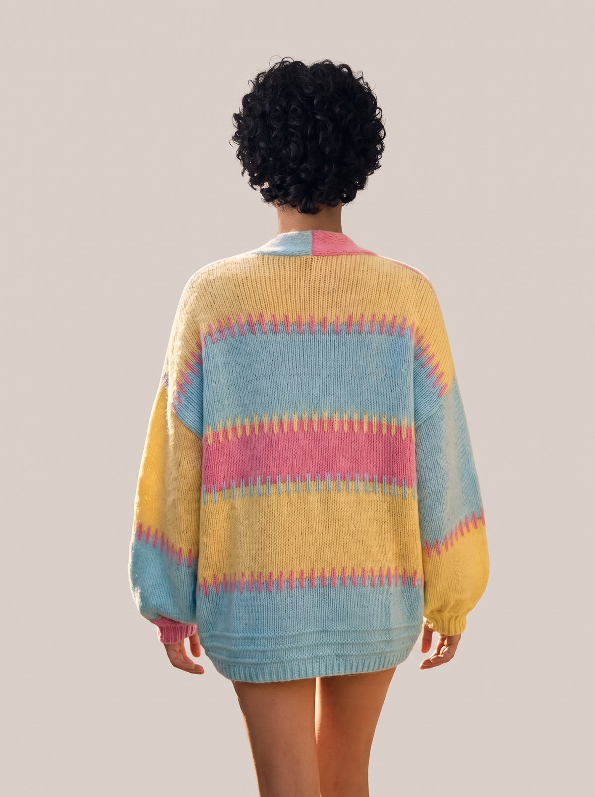 Back view of the pastel pink, yellow and aqua striped knit cardigan with dropped shoulders and balloon sleeves (Pink option)