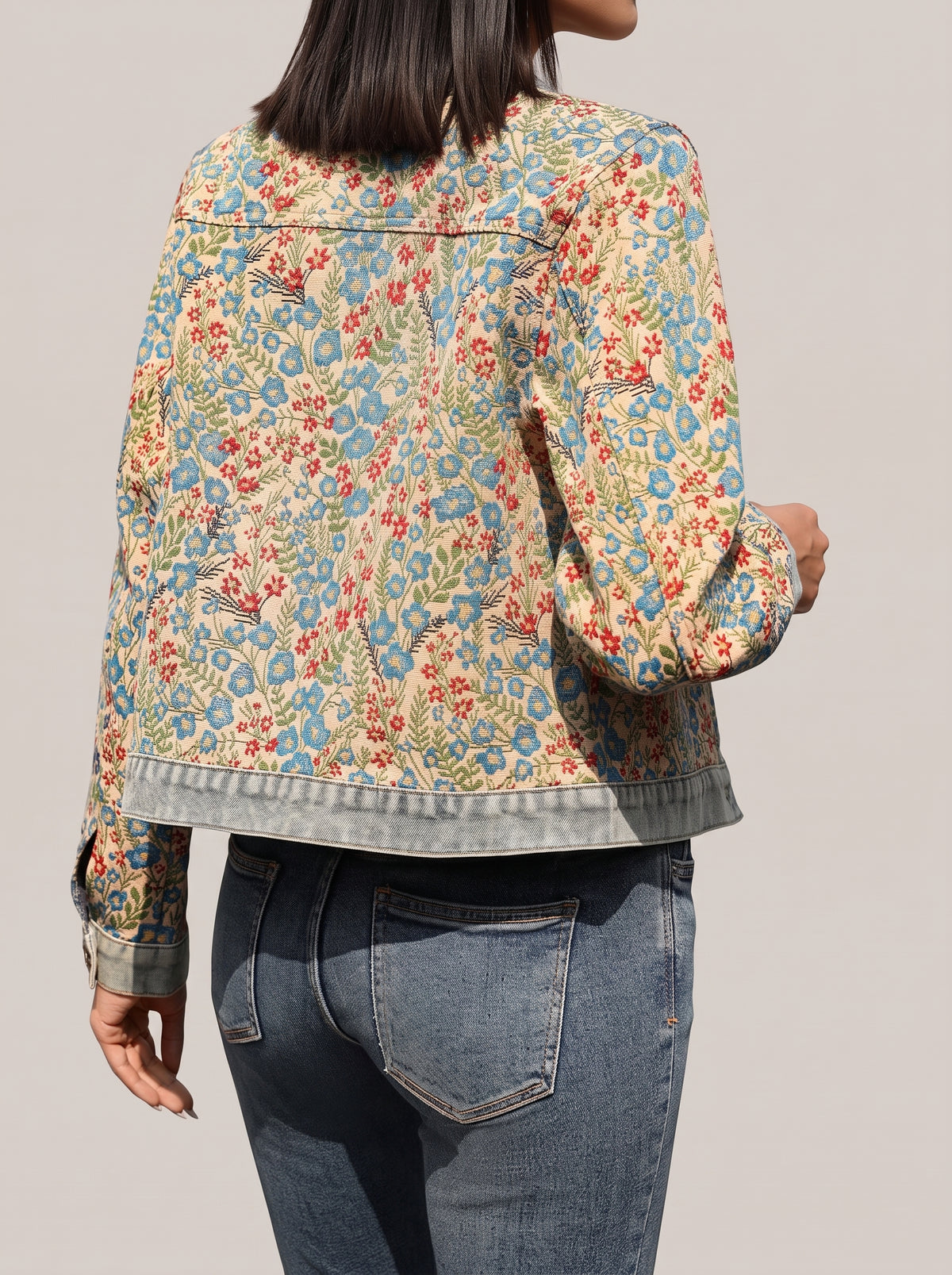 Back of the floral button up jacket showing the pattern and denim hem band