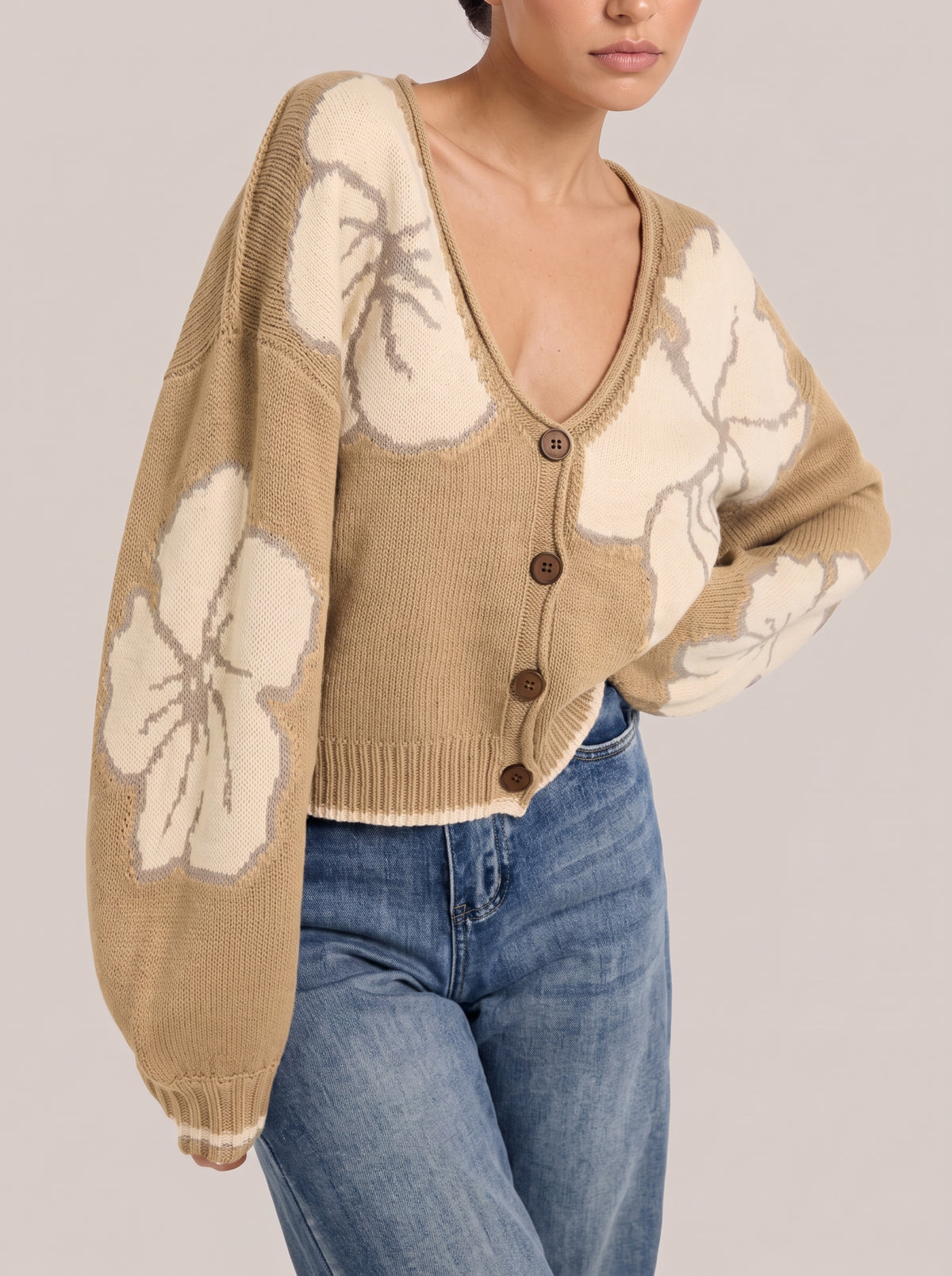 Side view of the khaki floral knit cardigan showing a large cream flower on the sleeve and a striped cuff