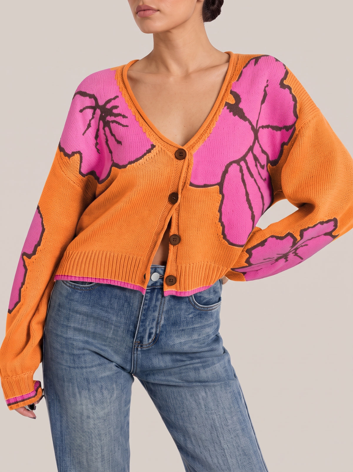 Orange V-neck button-front cropped knit cardigan with large pink flower motifs outlined in dark brown, front view