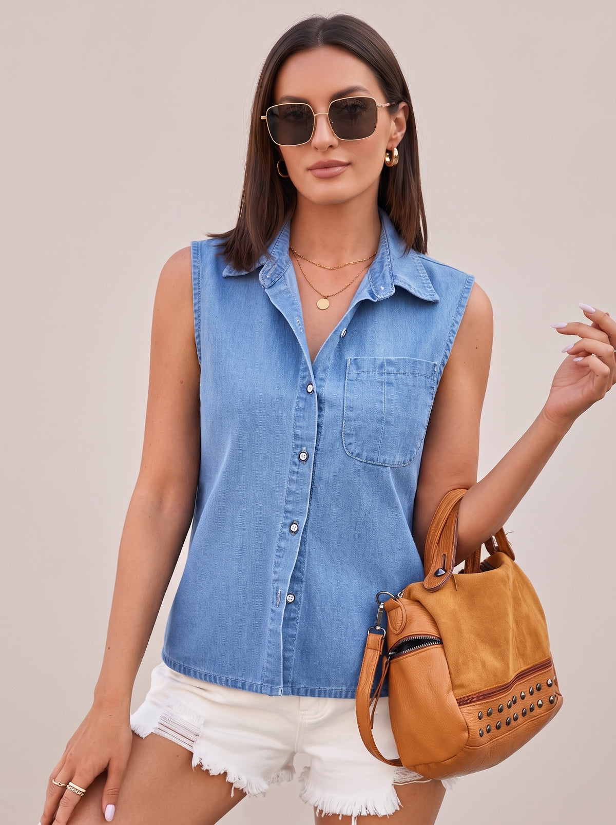 Light blue sleeveless denim top worn with a tan studded bag, front view