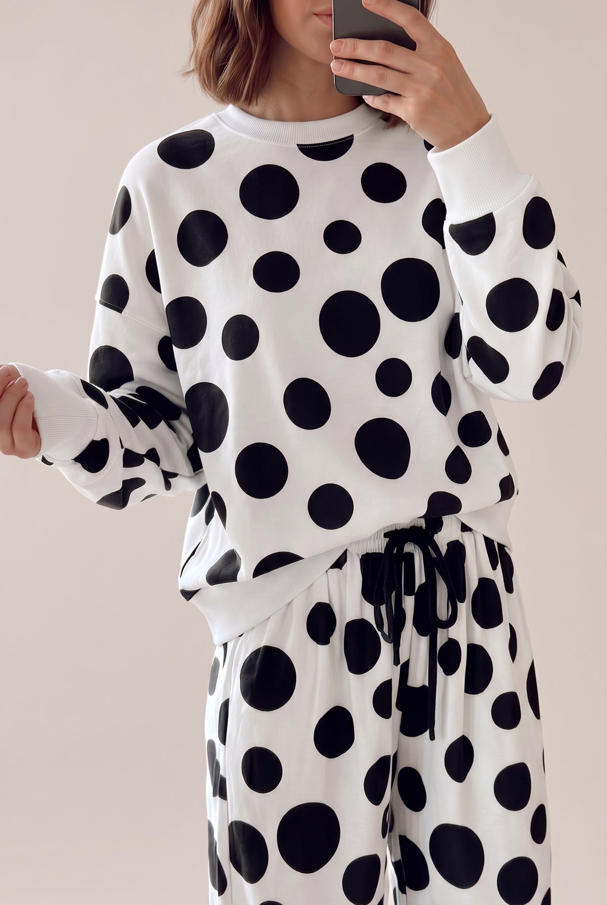 Close view of the black and white polka dot long sleeve top with the drawstring tie of the matching pants