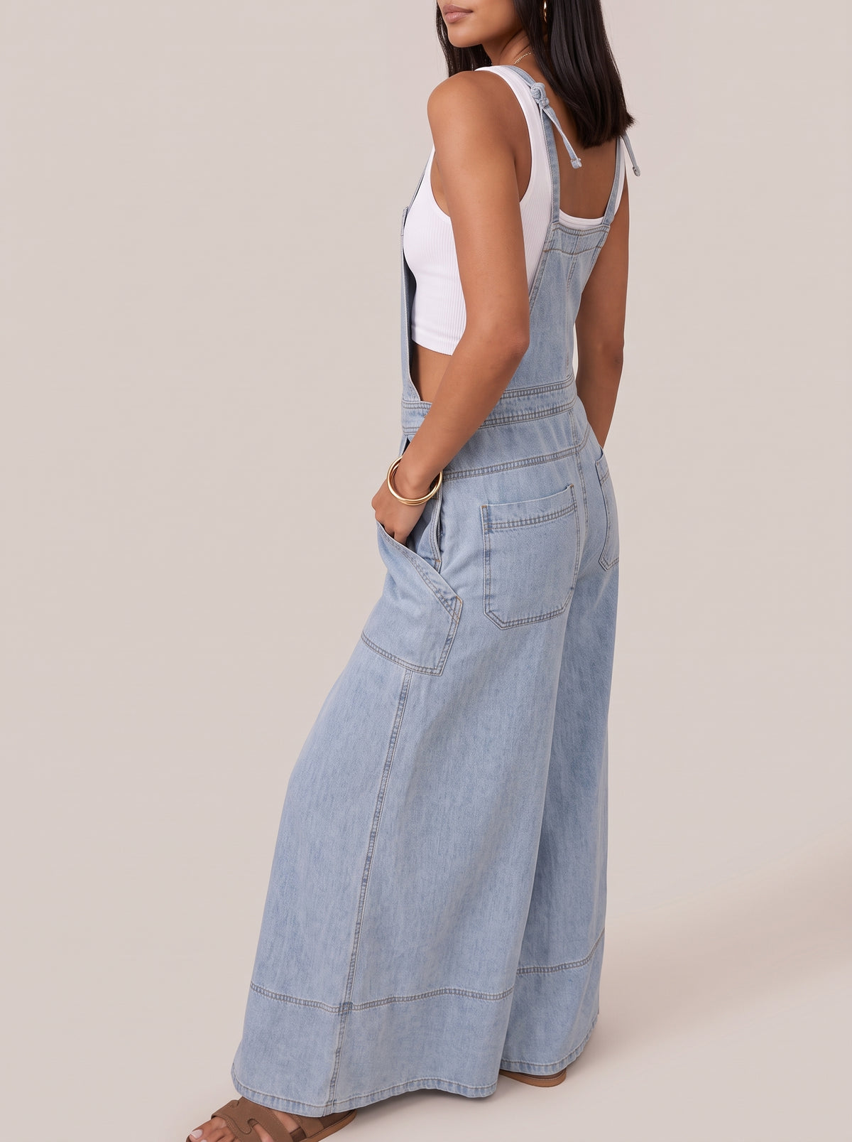 Side view of the light blue wide leg denim overalls showing the side pocket and wide hem