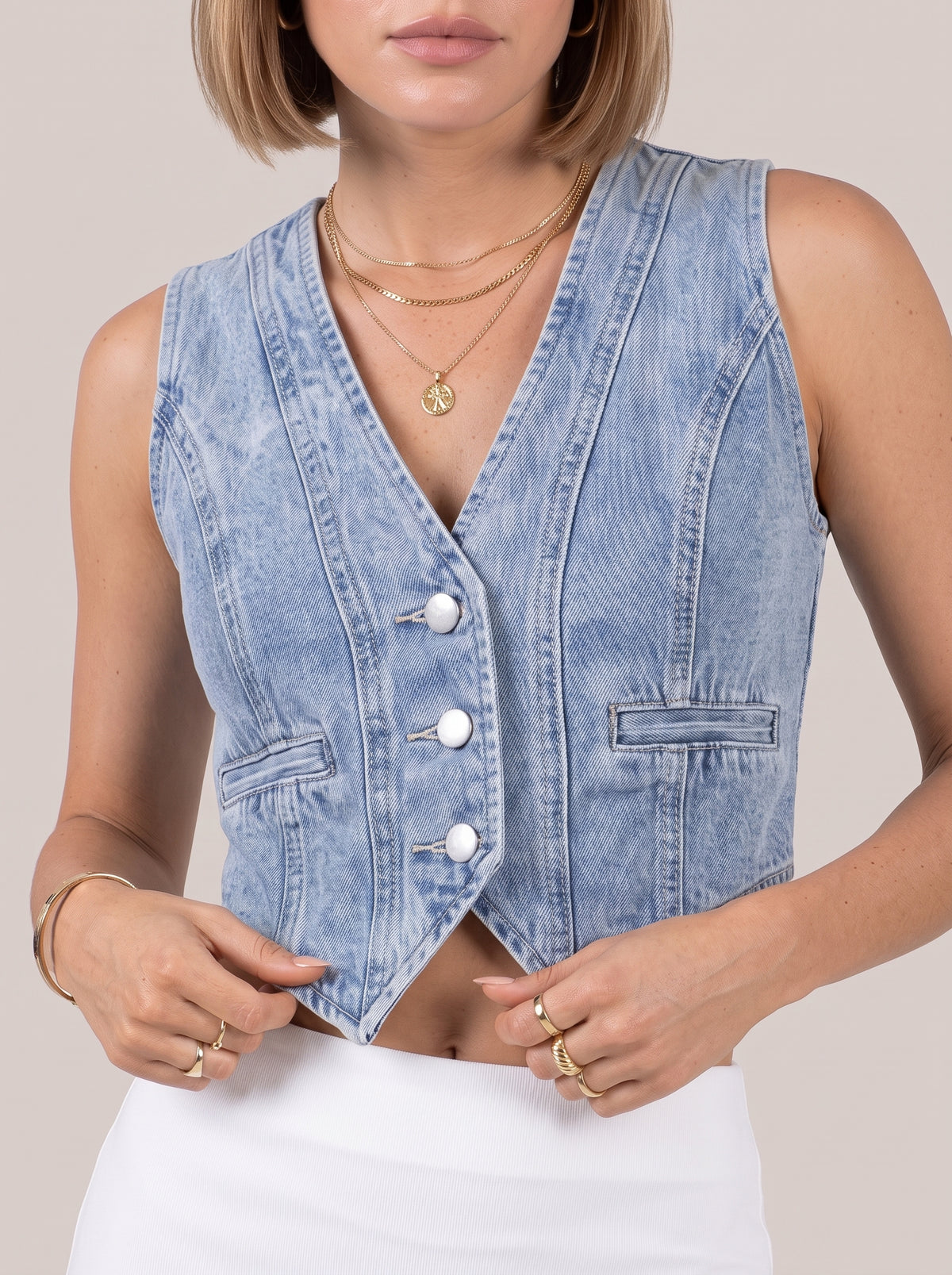 Close view of the light blue denim top front with V neckline, buttons and welt pockets