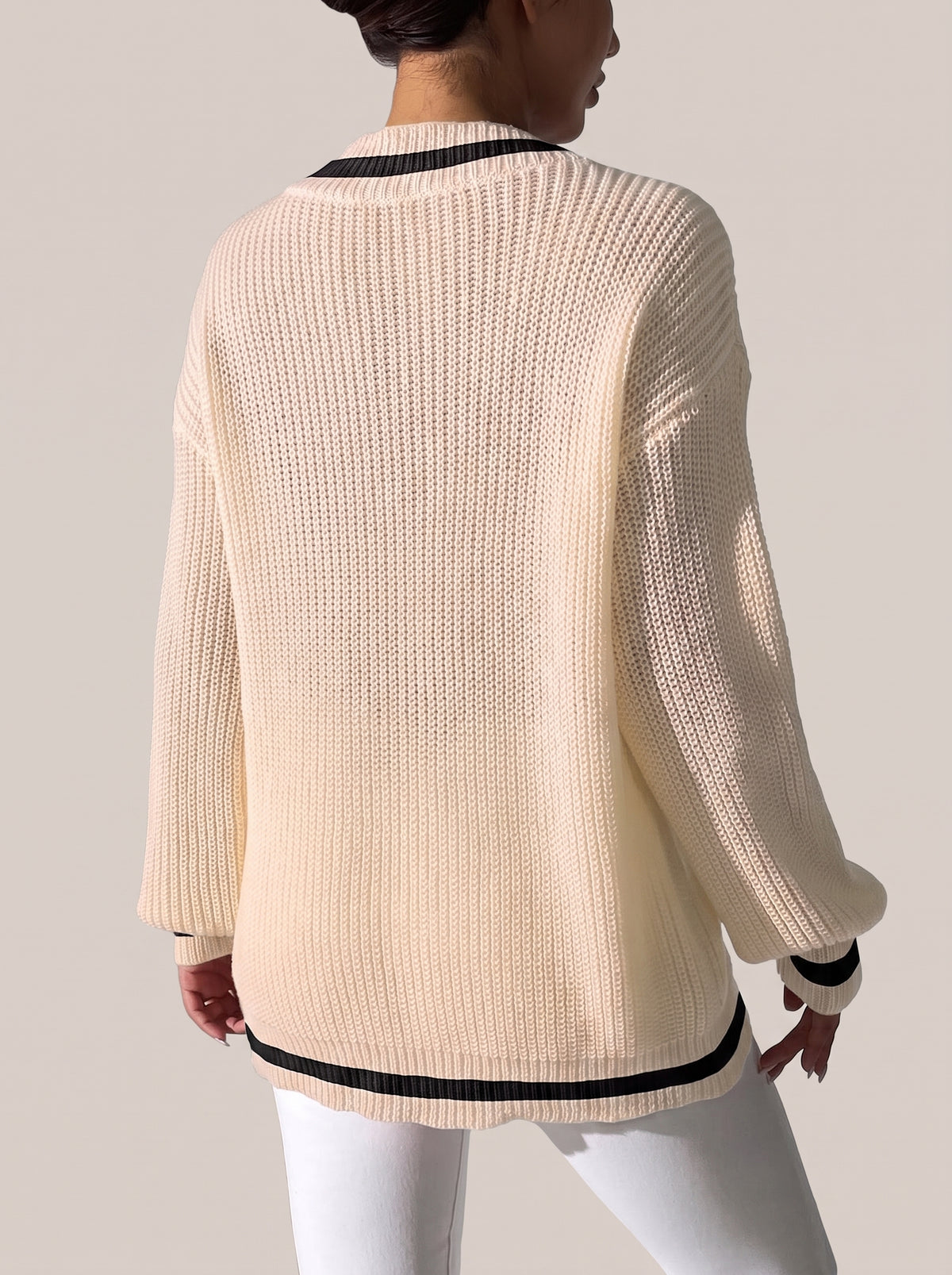 Back view of the tan V-neck sweater with black trim at the neckline, cuffs and hem