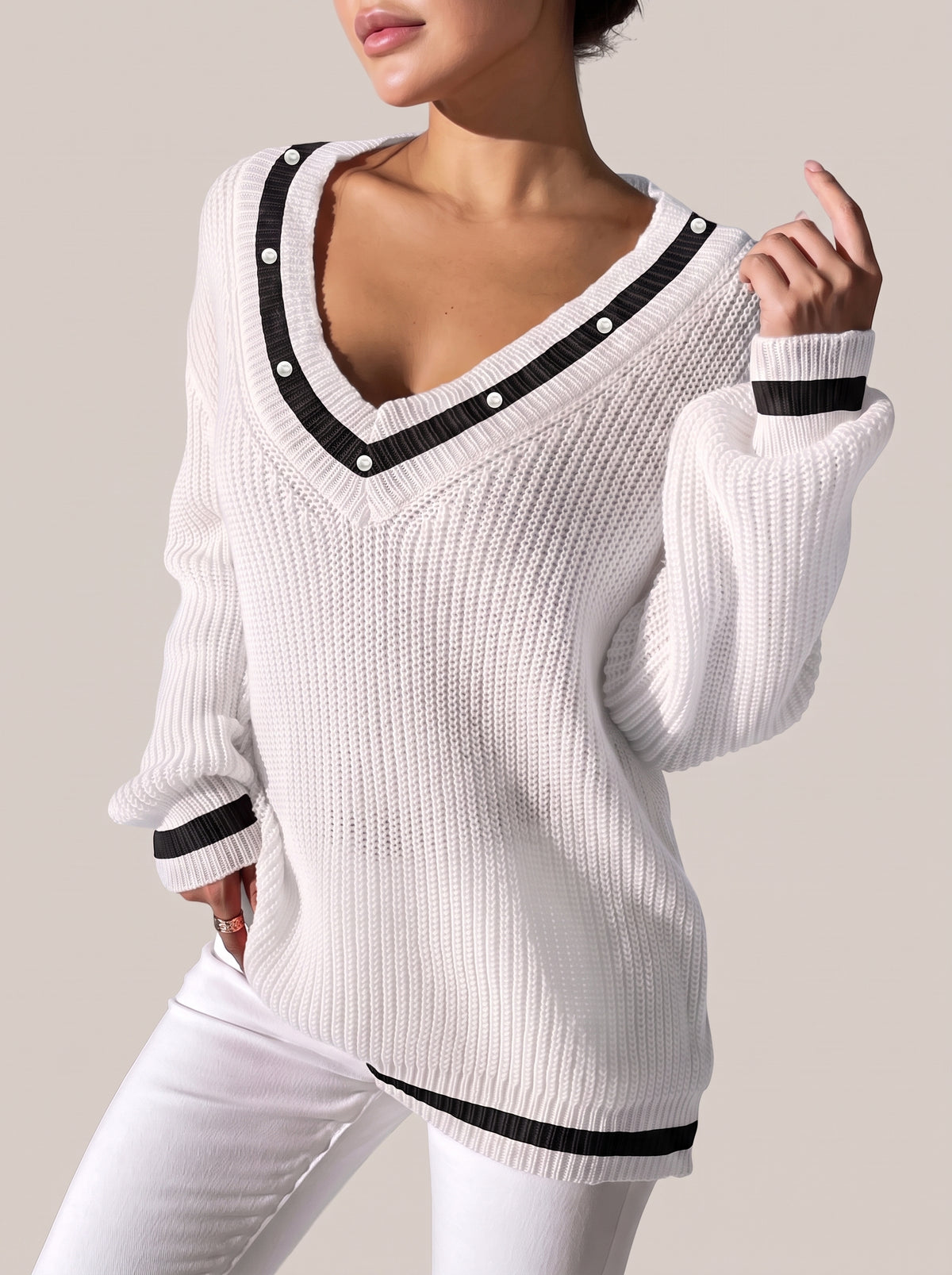 White V-neck rib-knit sweater with black contrast trim and pearl-look beads along the neckline, front view