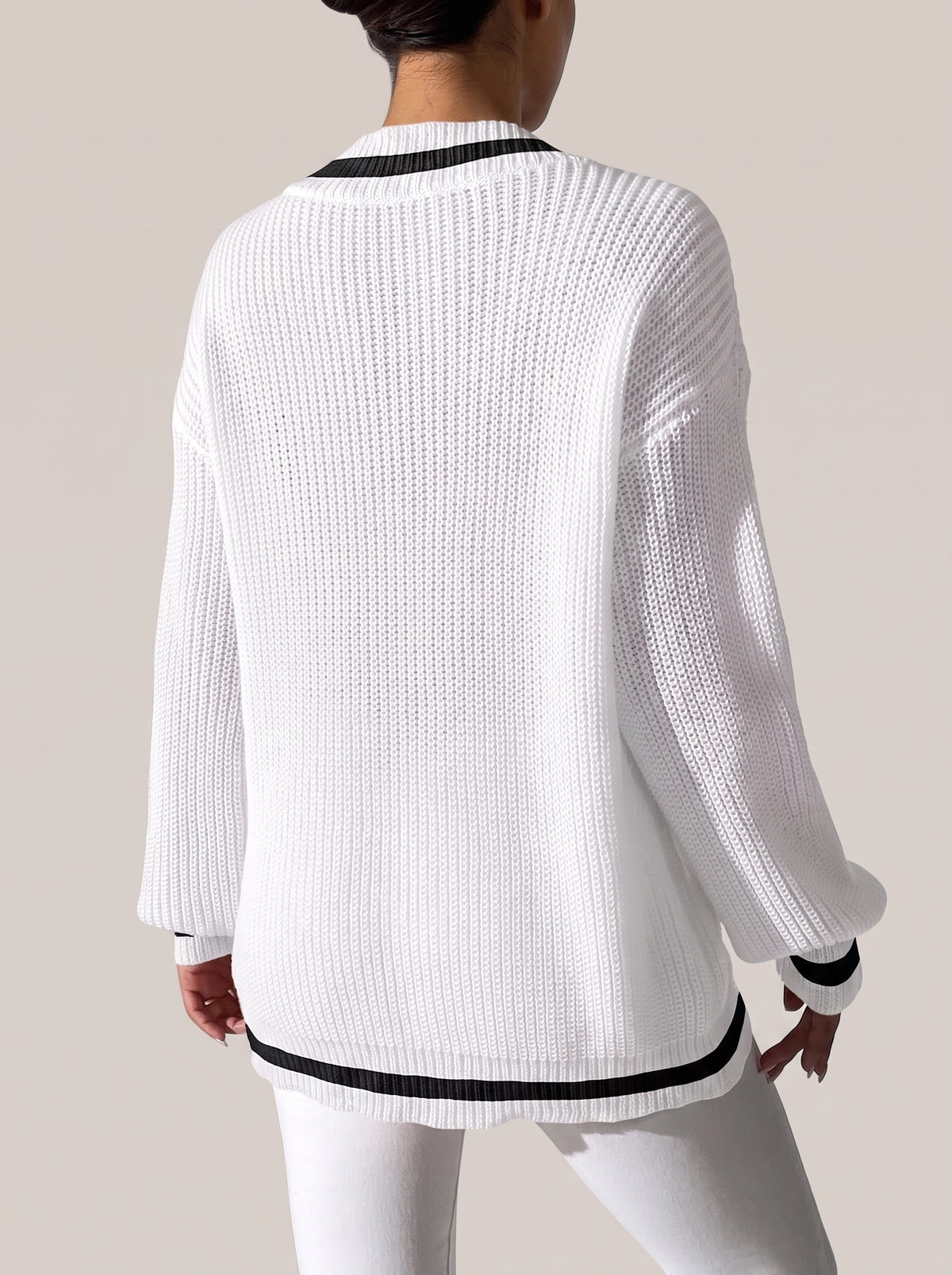 Back view of the white V-neck sweater with black trim at the cuffs and hem