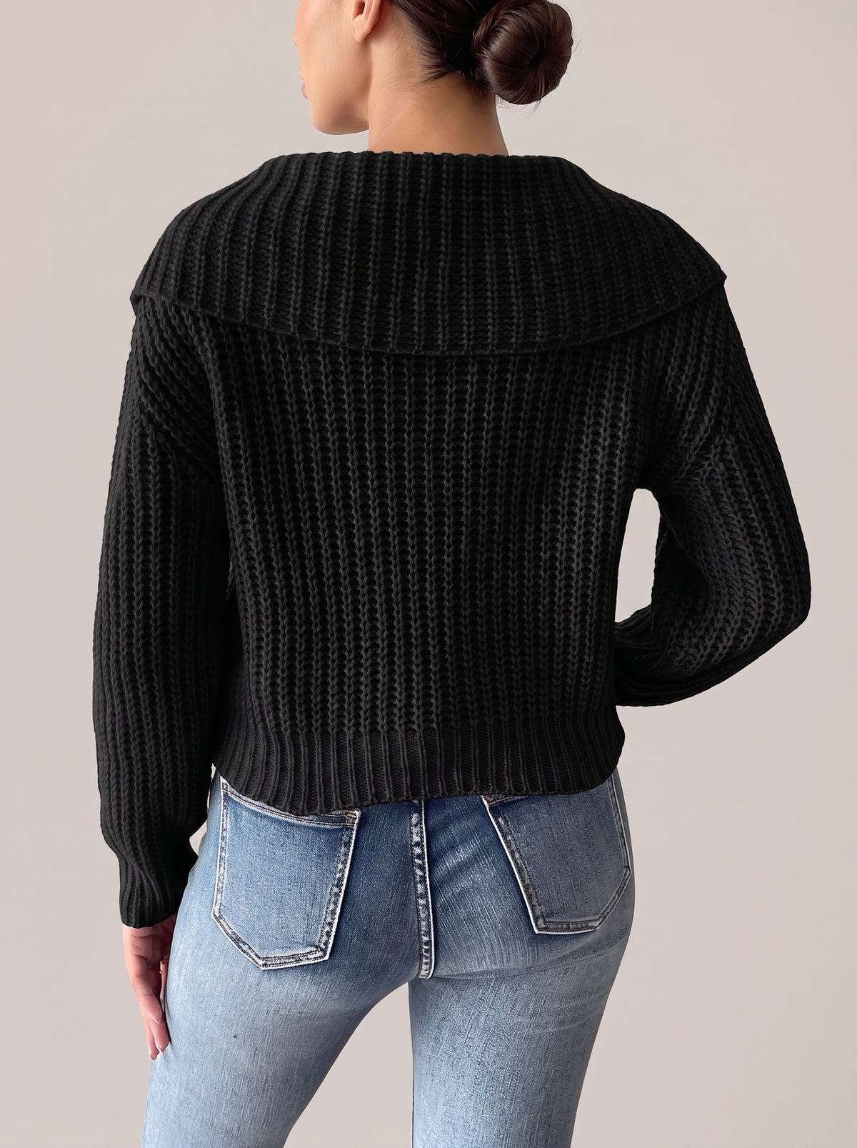 Back view of the black rib-knit sweater with the wide collar, ribbed cuffs and ribbed hem